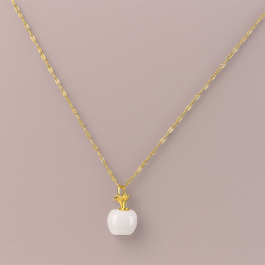 "Gold-tone necklace with white apple-shaped pendant close-up"