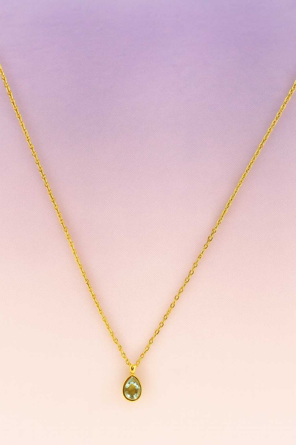 "Gold-tone necklace with clear teardrop crystal pendant close-up"