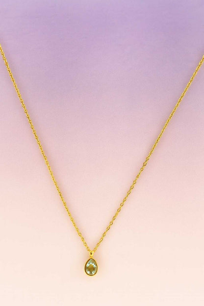 "Gold-tone necklace with clear teardrop crystal pendant close-up"