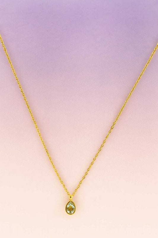 "Gold-tone necklace with clear teardrop crystal pendant close-up"