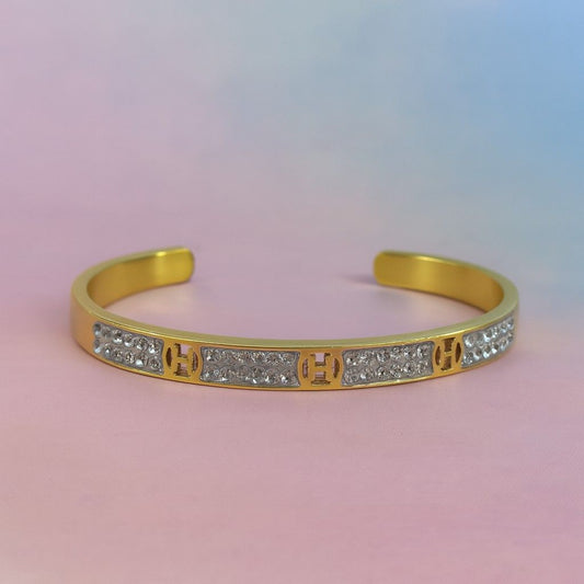Gold-tone open cuff bracelet with multiple 'H' motifs and stones