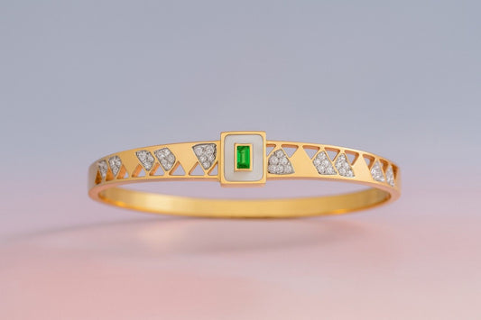 Gold-tone bracelet with geometric cut-out design and green stone centerpiece