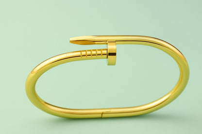 Gold-tone bracelet in nail-inspired design on green background