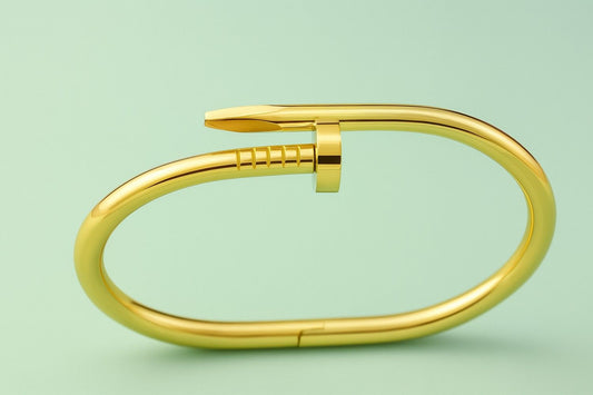 Gold-tone bracelet in nail-inspired design on green background
