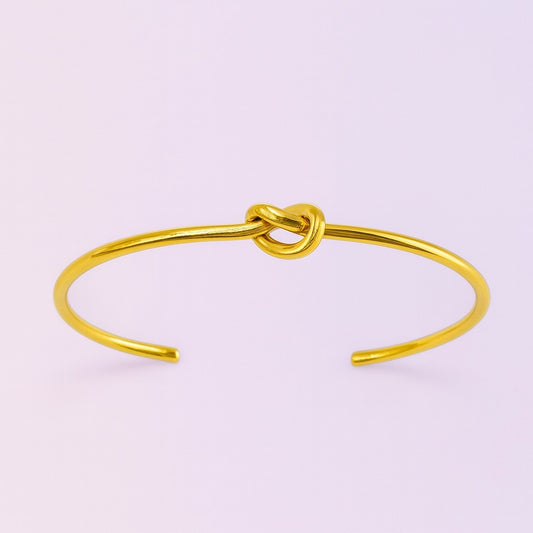Minimalist gold-tone open cuff bracelet with central knot design