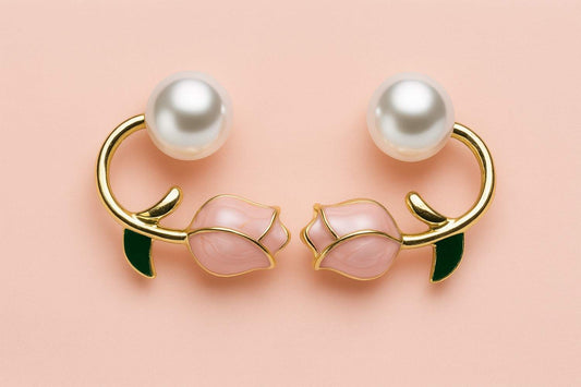 "Elegant gold-tone pearl and pink rose bud earrings with green enamel leaf detail on pastel background"