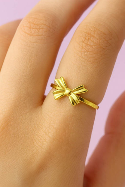 "Model wearing minimal gold-tone bow ring with adjustable band"

