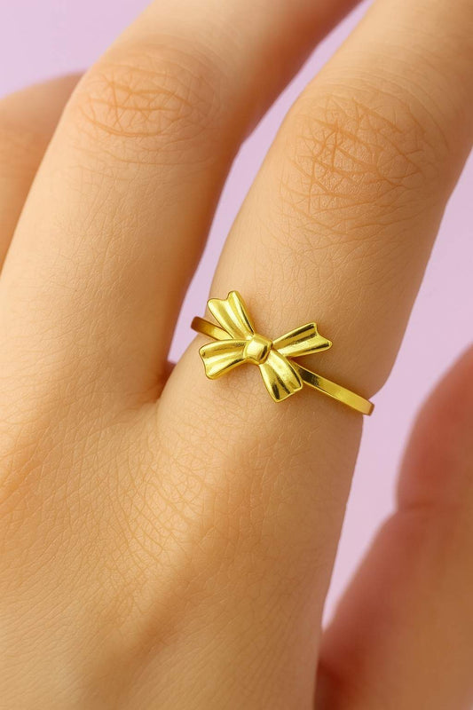"Model wearing minimal gold-tone bow ring with adjustable band"

