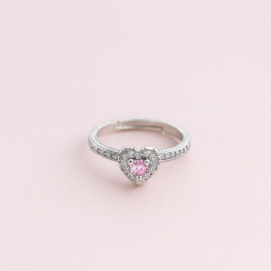 "Model wearing silver-tone ring with pink heart stone and crystal halo"