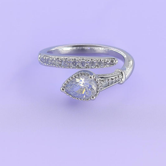 "Silver-tone teardrop stone ring with crystal band on pastel background"