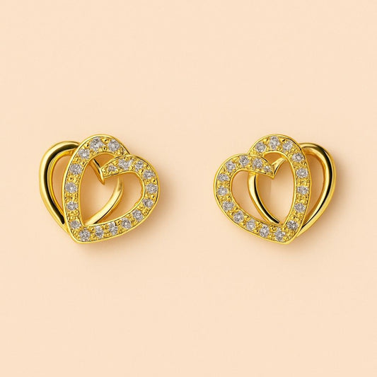 "Gold-tone double heart stud earrings with sparkling stones on plain background"
