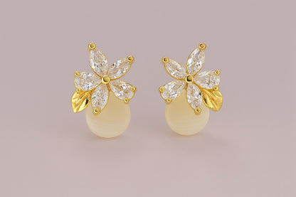 Gold-tone floral stud earrings with crystal petals and golden leaf detail on plain background