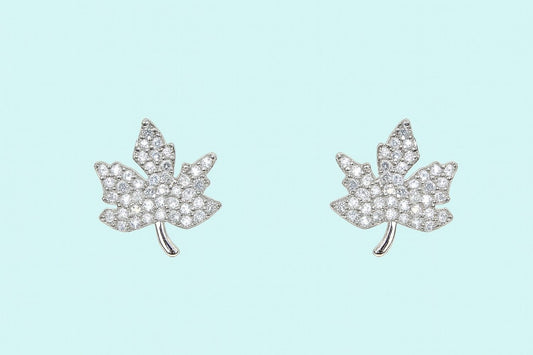 silver-tone maple leaf crystal stud earrings on plain background