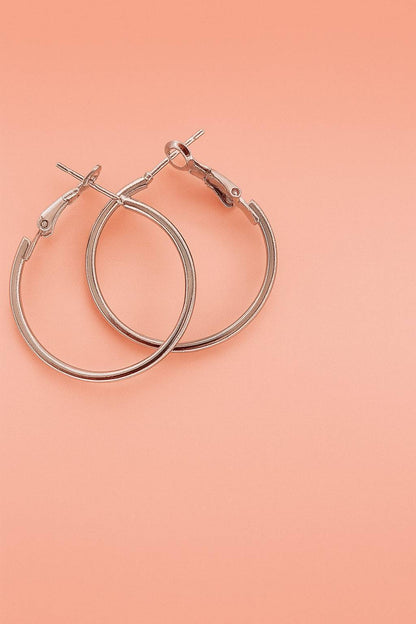 Silver-tone hoop earrings with latch-back closure on peach background