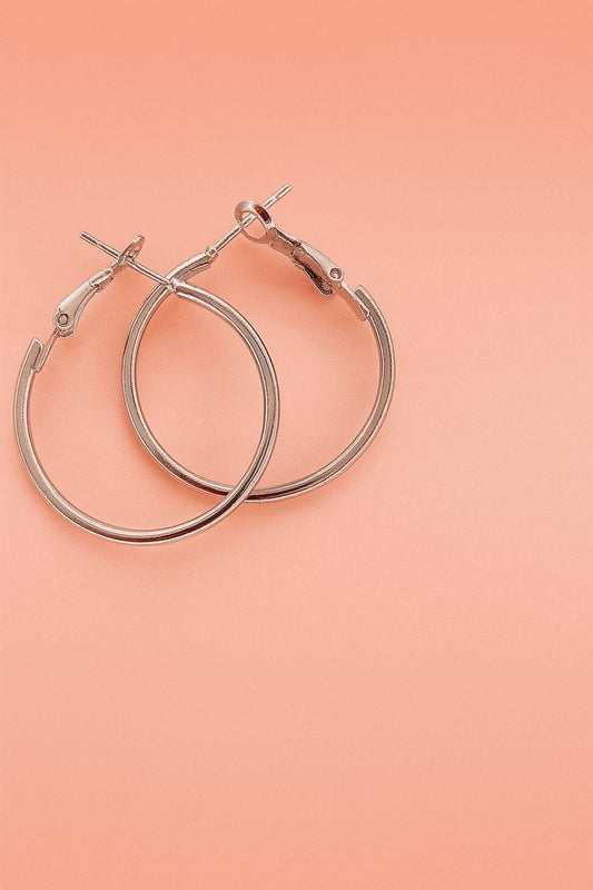 Silver-tone hoop earrings with latch-back closure on peach background