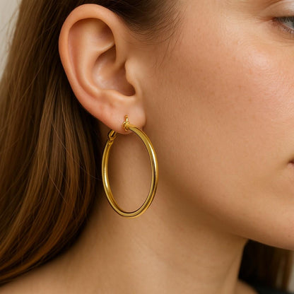 Woman wearing gold-tone large hoop earrings in side profile view

