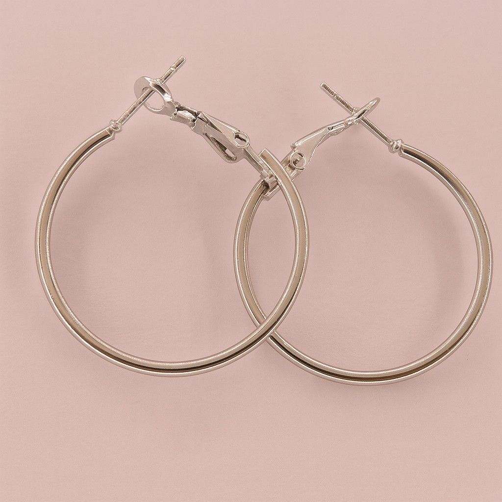 Minimalist silver-tone large hoop earrings on pink background