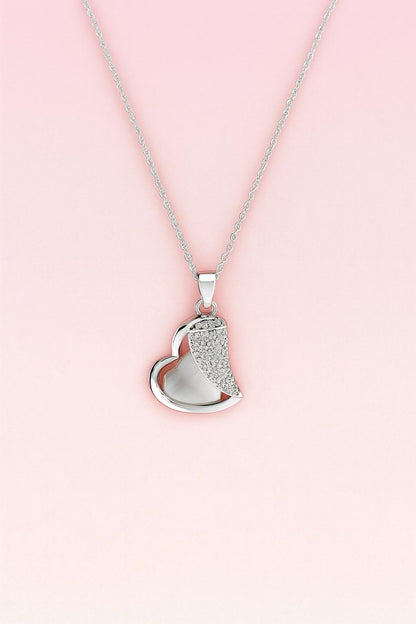 Silver-tone heart pendant necklace with crystal accents on pink background