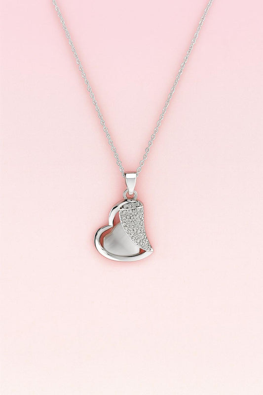Silver-tone heart pendant necklace with crystal accents on pink background