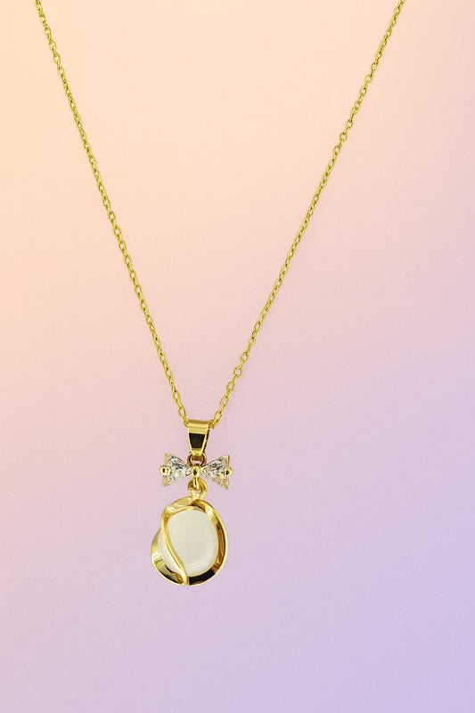 Gold-tone bow pendant necklace with white stone centerpiece on plain background