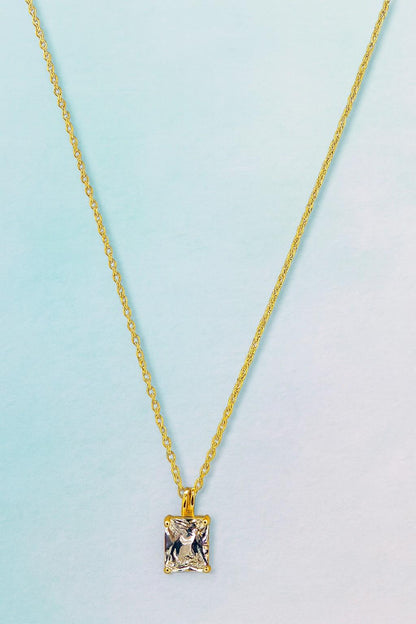 Elegant gold-tone chain necklace with square-cut crystal pendant on blue background