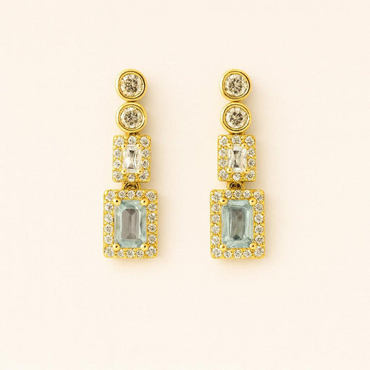 Pair of elegant gold-tone crystal drop earrings on beige background