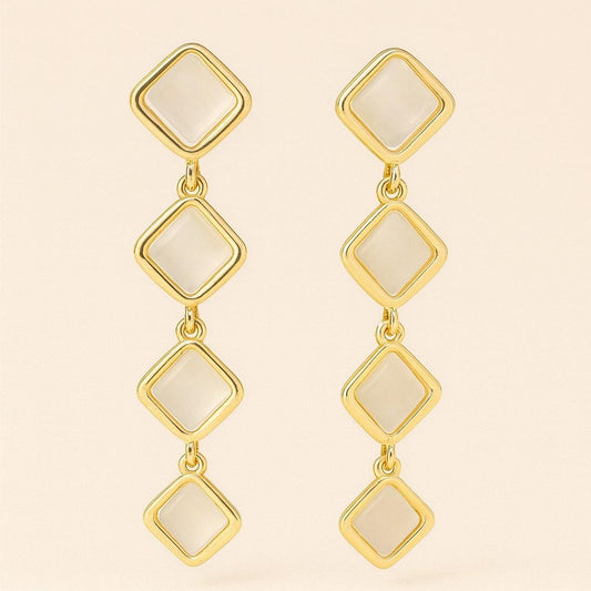 Pair of gold-tone quad square drop earrings with pearl finish on beige background