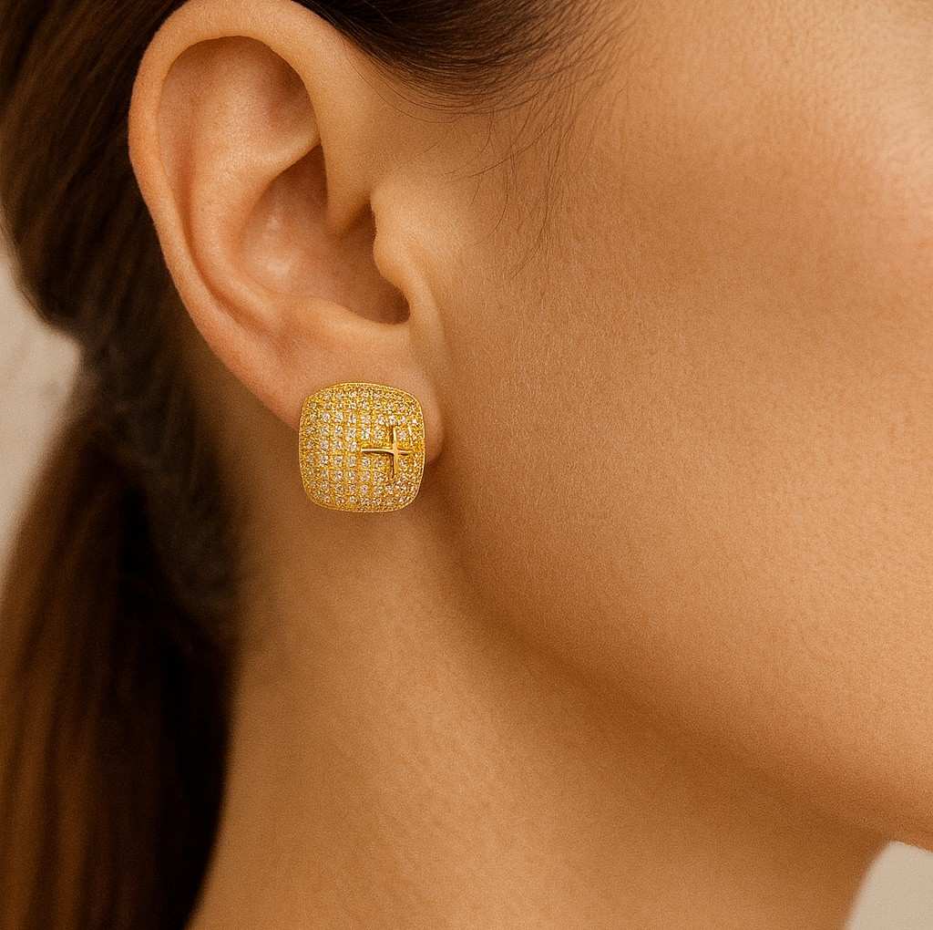 Pair of luxury gold-tone crystal cross stud earrings on beige background