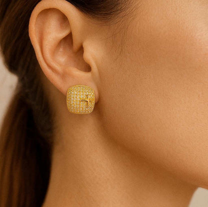 Pair of luxury gold-tone crystal cross stud earrings on beige background