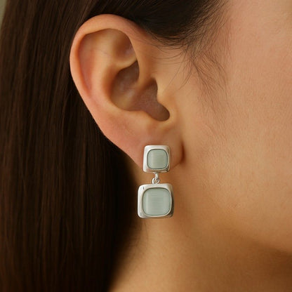 Model wearing silver-tone dual square drop earrings with icy blue enamel finish