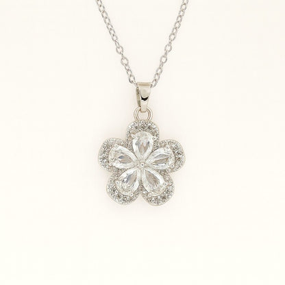 Silver-tone floral crystal pendant necklace on beige background